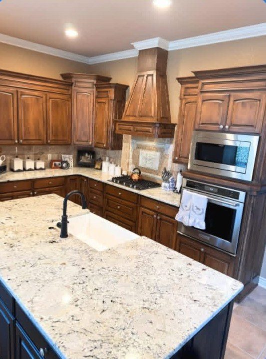 Kitchen island with a light granite countertop and farmhouse sink